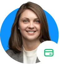 Moteris rudais plaukais iki pečių, vilkinti pilką švarkelį ir baltą palaidinę, šypsosi mėlyname fone. Vaizdo kampe yra kredito kortelės piktograma.